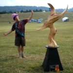 Sculpture - The Crossover, with Artist Gregor posing in a grassy, open field