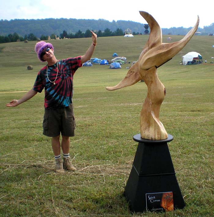 Sculpture - The Crossover, with Artist Gregor posing in a grassy, open field